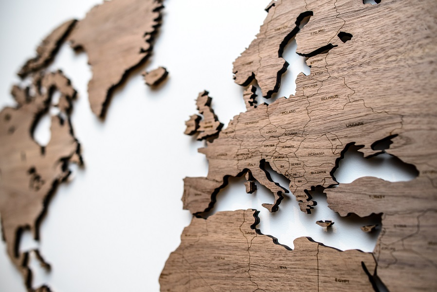 Detalus medinis pasaulio žemėlapis ant sienos su šalių pavadinimais ir smeigtukais Riešutas